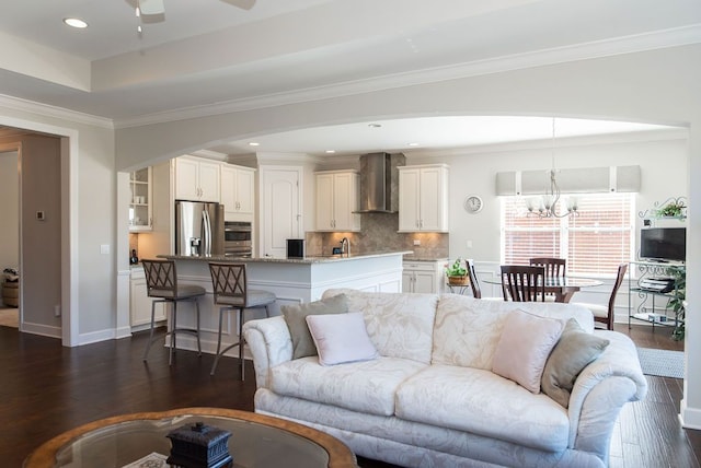 living room with dark wood-style floors, baseboards, recessed lighting, crown molding, and ceiling fan with notable chandelier