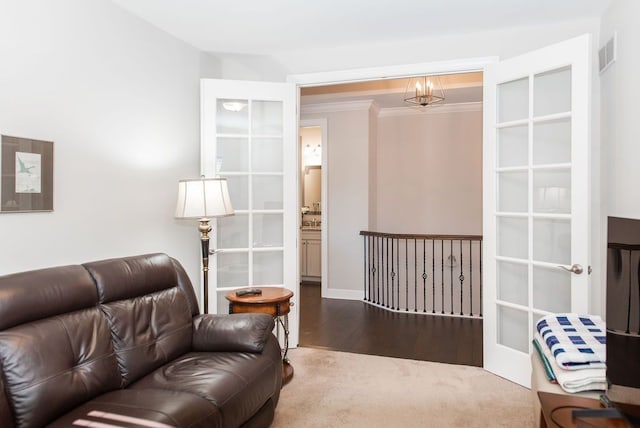 living room featuring an inviting chandelier, crown molding, wood finished floors, and visible vents