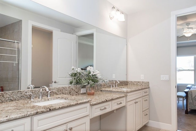 bathroom with double vanity, tiled shower, baseboards, and a sink