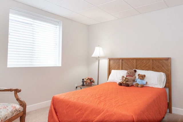 carpeted bedroom with a paneled ceiling and baseboards