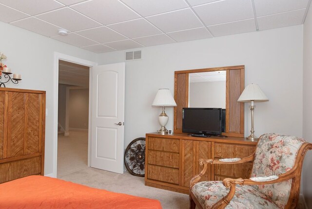 bedroom featuring visible vents, a drop ceiling, and light carpet