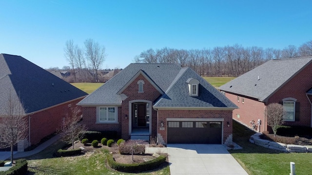 view of front of property featuring brick siding, a front lawn, concrete driveway, and roof with shingles