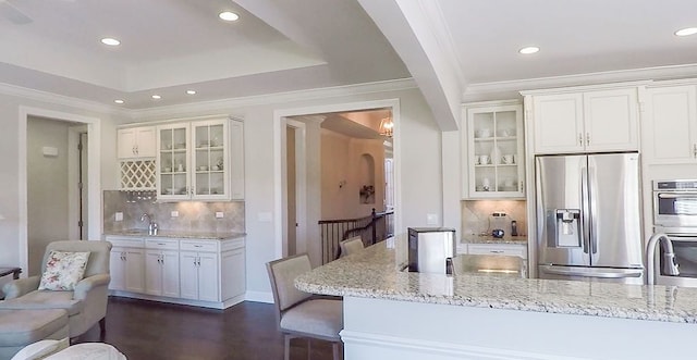 kitchen with arched walkways, white cabinets, stainless steel appliances, and glass insert cabinets