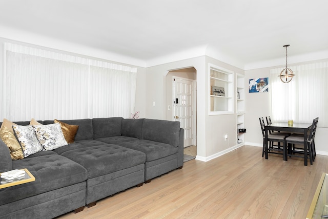 living area with light wood-type flooring, arched walkways, and baseboards