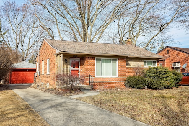 bungalow-style house featuring a front yard, a chimney, an outdoor structure, a detached garage, and brick siding