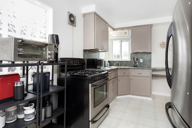 kitchen featuring decorative backsplash, light floors, gray cabinets, and appliances with stainless steel finishes