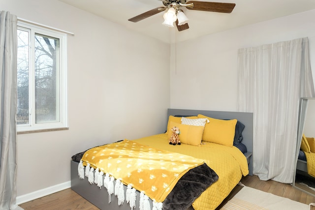 bedroom featuring ceiling fan, baseboards, and wood finished floors