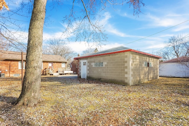 rear view of property featuring concrete block siding and an outdoor structure