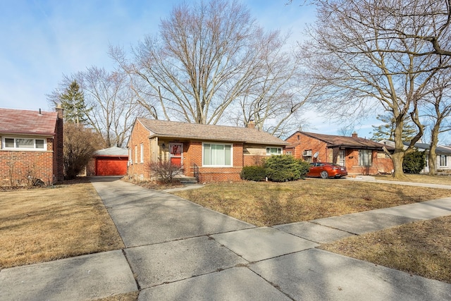 ranch-style home with brick siding, a garage, an outbuilding, and a front yard