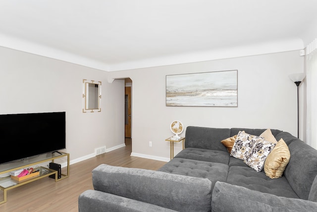 living area with arched walkways, baseboards, and wood finished floors