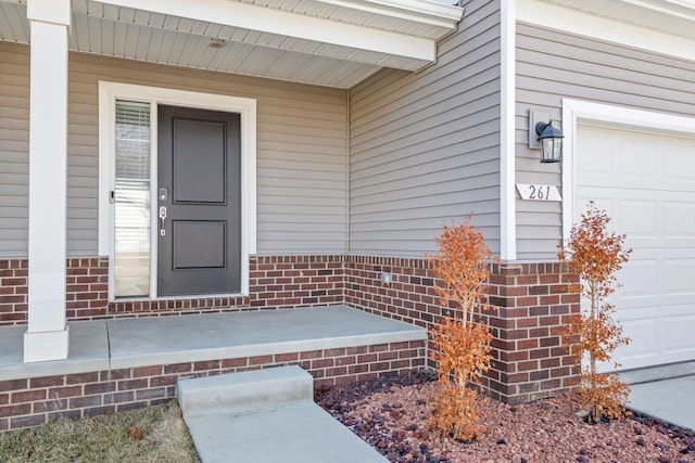 property entrance with a garage and brick siding