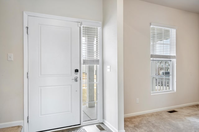 carpeted entrance foyer featuring visible vents and baseboards