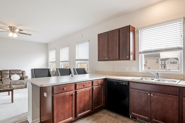 kitchen with a peninsula, light countertops, black dishwasher, and a sink