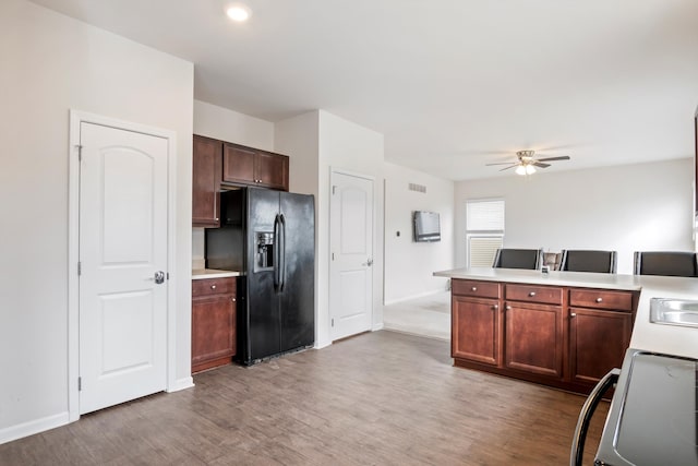 kitchen featuring light countertops, range, light wood finished floors, and black refrigerator with ice dispenser