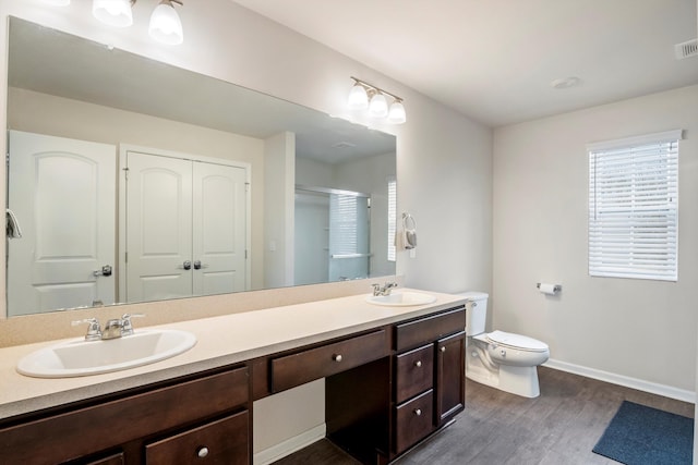 full bathroom featuring double vanity, toilet, wood finished floors, and a sink