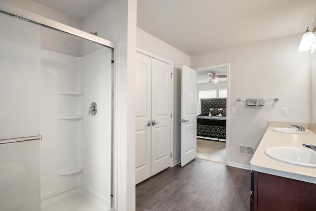 bathroom featuring a stall shower, wood finished floors, ensuite bathroom, and a sink