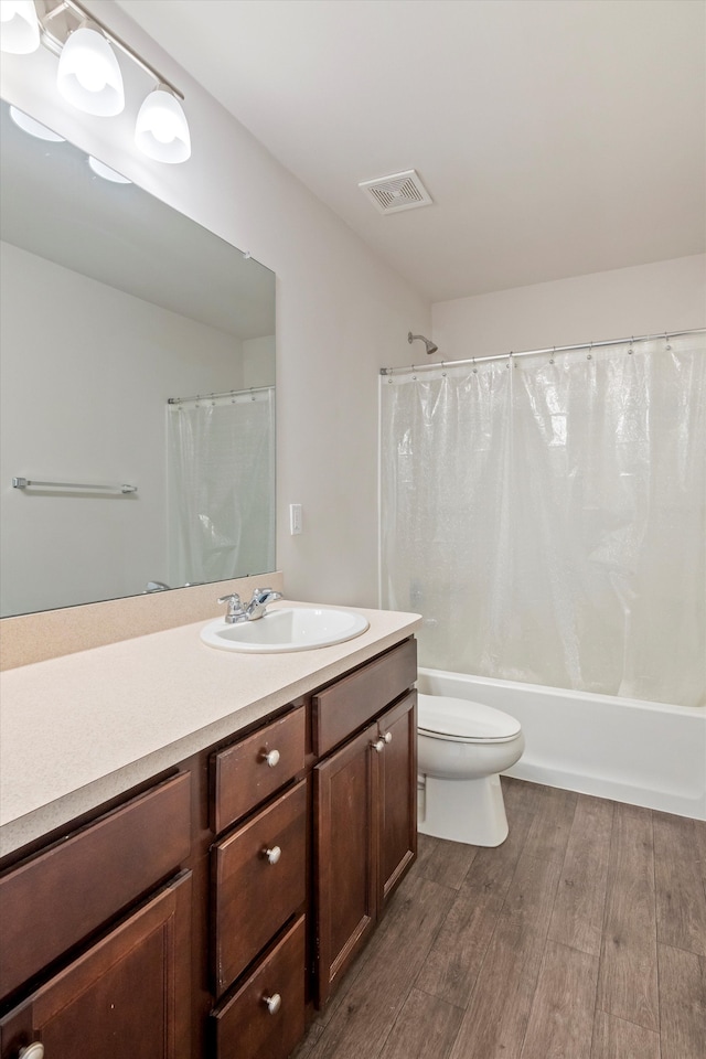 full bathroom with visible vents, toilet, shower / bath combo, wood finished floors, and vanity