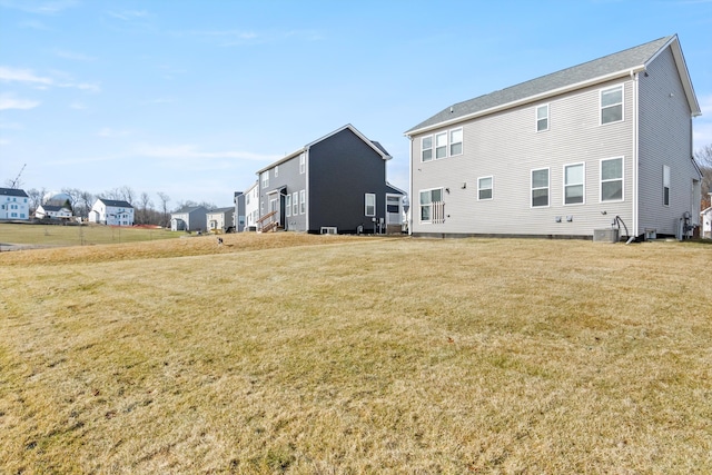 back of property featuring a yard and central AC