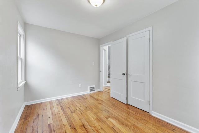 unfurnished bedroom with light wood-type flooring, visible vents, and baseboards