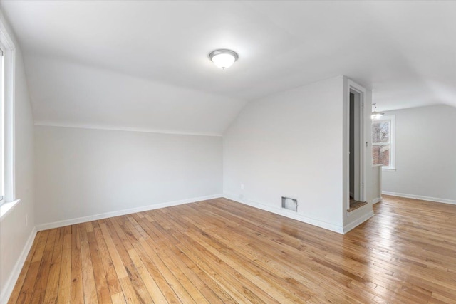 additional living space with vaulted ceiling, light wood-style flooring, and baseboards