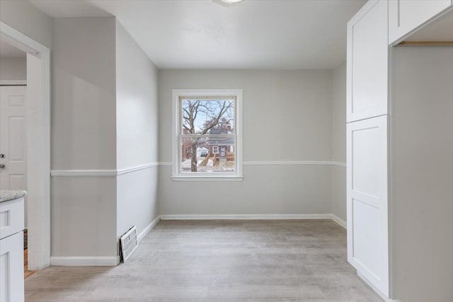 unfurnished dining area featuring visible vents, light wood-type flooring, and baseboards