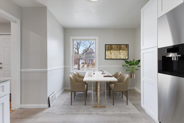 dining area with light wood-style floors, visible vents, and baseboards