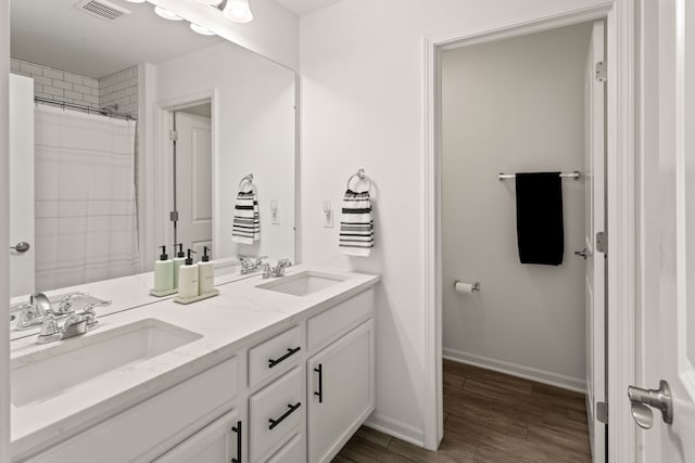 bathroom with baseboards, wood finished floors, visible vents, and a sink