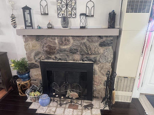 details featuring a stone fireplace and wood finished floors