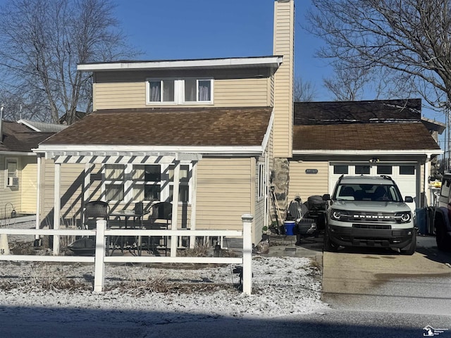 view of front of property featuring roof with shingles, concrete driveway, a chimney, and fence