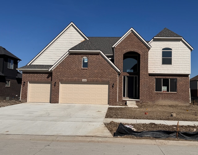 traditional-style house with brick siding, an attached garage, concrete driveway, and roof with shingles