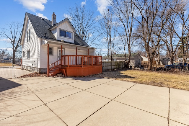 back of house with a gate, fence, roof with shingles, a yard, and a chimney