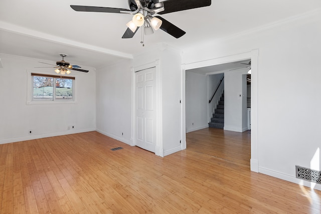 spare room with stairs, light wood-style flooring, baseboards, and visible vents