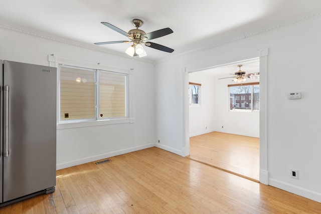 empty room with a ceiling fan, baseboards, visible vents, and wood-type flooring