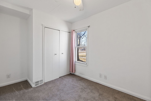 unfurnished bedroom featuring visible vents, a closet, carpet, baseboards, and ceiling fan