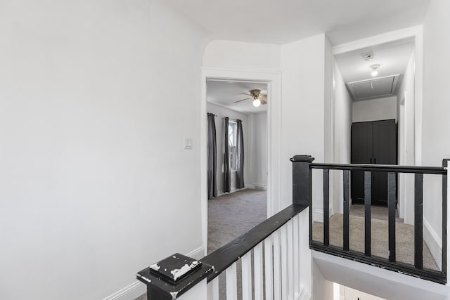 hall featuring baseboards, carpet, attic access, and an upstairs landing