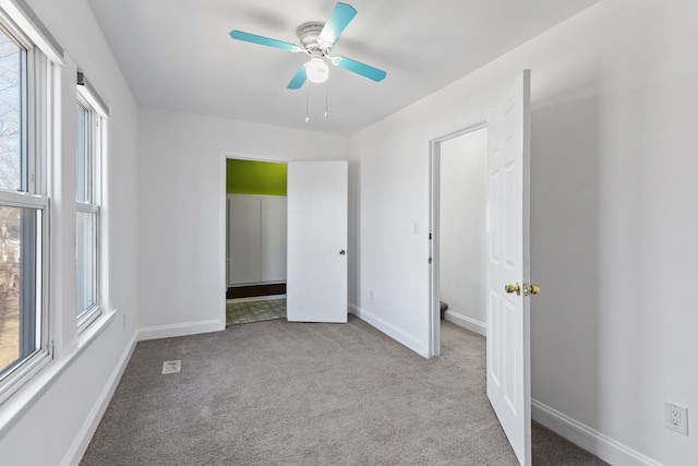 unfurnished bedroom with a ceiling fan, ensuite bath, carpet, and baseboards