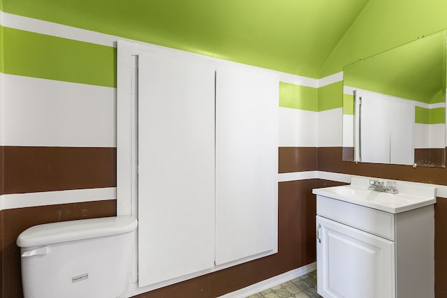 bathroom with tile patterned floors, lofted ceiling, toilet, and vanity