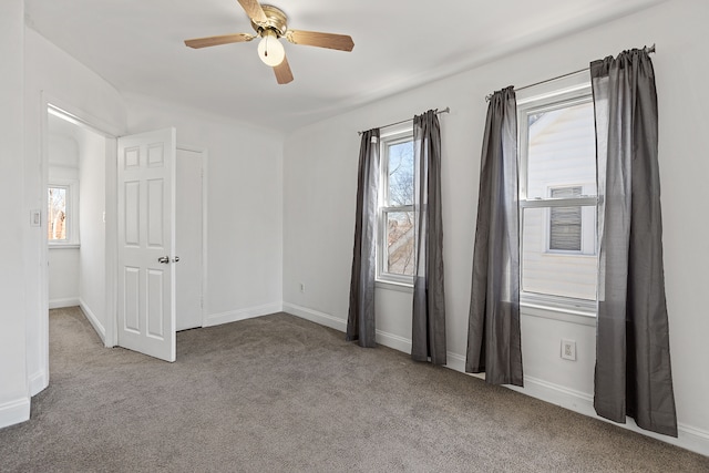 unfurnished bedroom with multiple windows, a ceiling fan, baseboards, and carpet floors