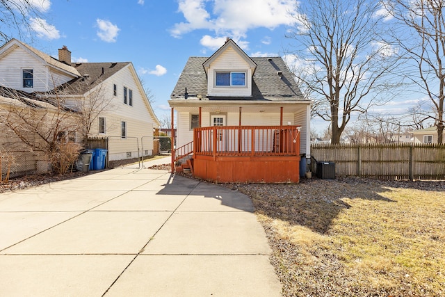 exterior space featuring central air condition unit, covered porch, a shingled roof, and fence