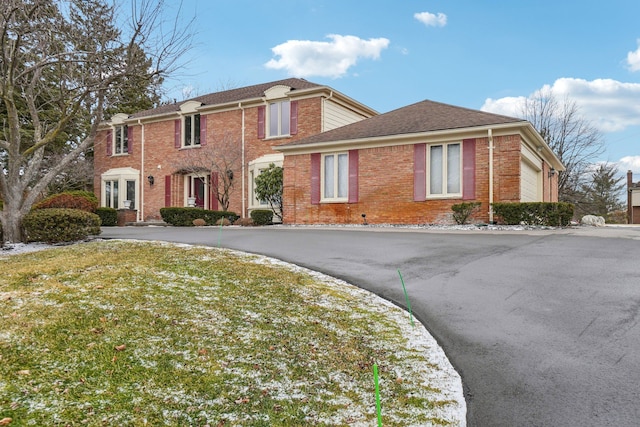 view of front of house with a front lawn, aphalt driveway, brick siding, and a shingled roof