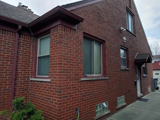 view of home's exterior with brick siding and a shingled roof