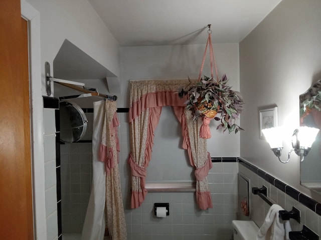 bathroom featuring a wainscoted wall and tile walls