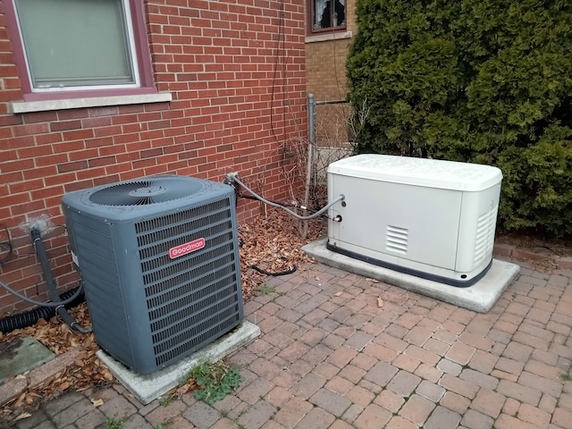 details with a jacuzzi, cooling unit, brick siding, and a power unit