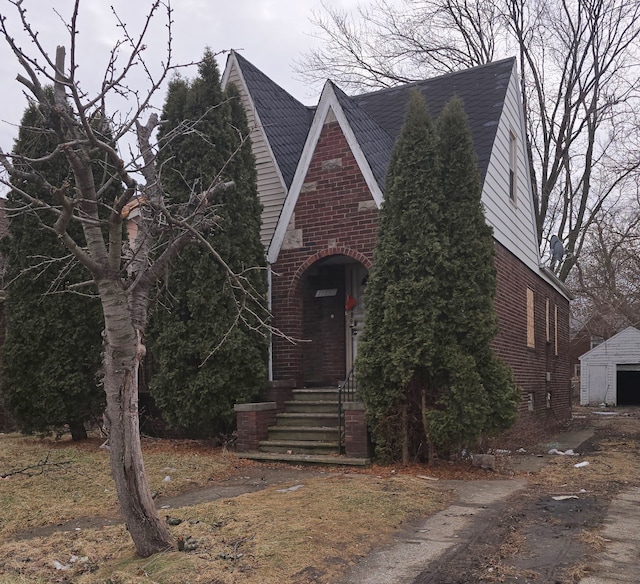 tudor home featuring brick siding and an outbuilding