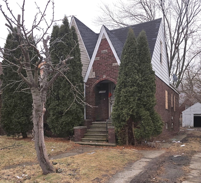 tudor home with an outbuilding and brick siding