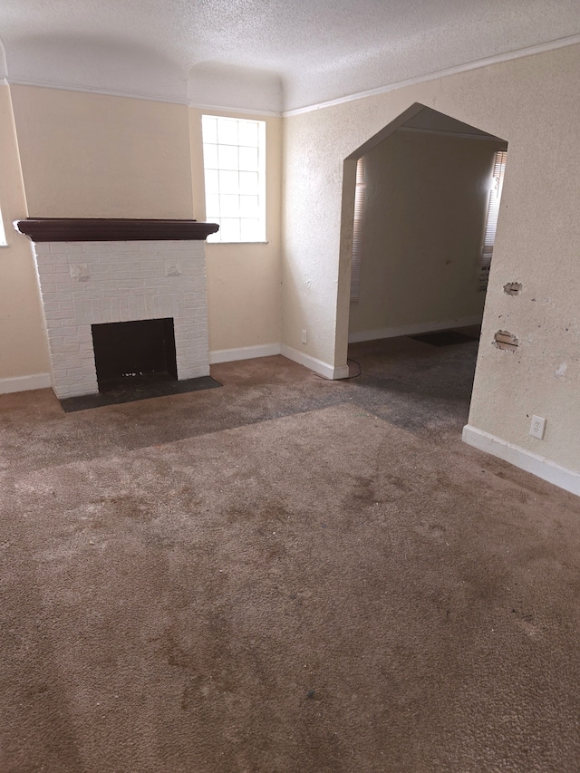 unfurnished living room with baseboards, carpet floors, a textured ceiling, and a brick fireplace