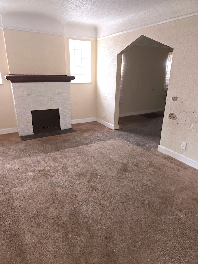 unfurnished living room featuring carpet flooring, a brick fireplace, a textured ceiling, and baseboards