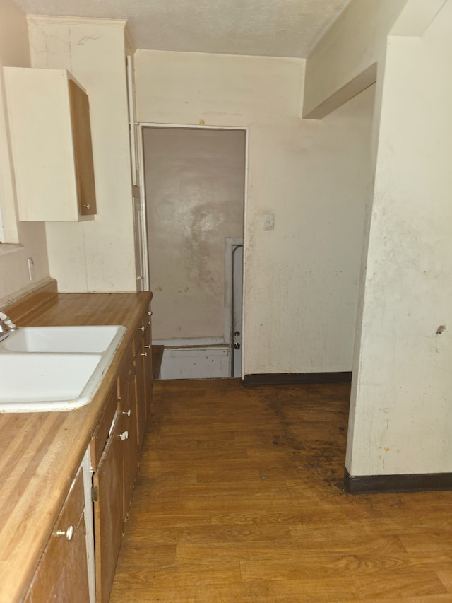 kitchen with a sink, wood counters, brown cabinets, and light wood-style floors