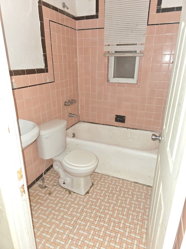 full bathroom featuring tile patterned flooring, toilet, tile walls, and washtub / shower combination