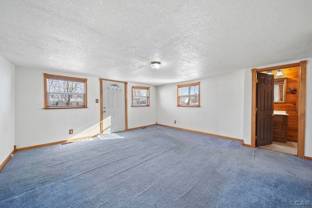 carpeted empty room featuring visible vents, baseboards, and a textured ceiling